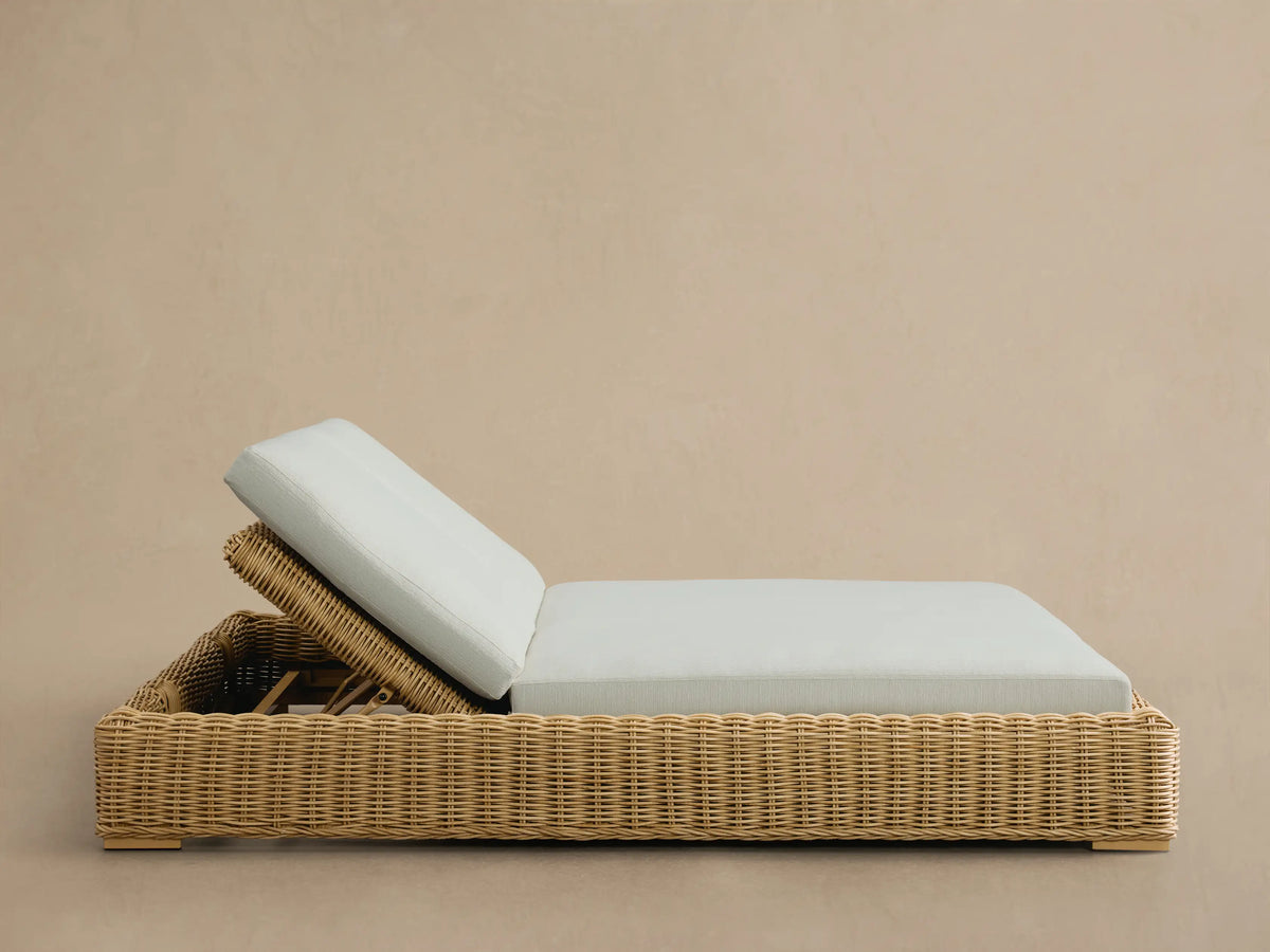 Close-up of the adjustable reclining back of the Montauk Outdoor Double Chaise, showing natural resin wicker and a light blue cushion.