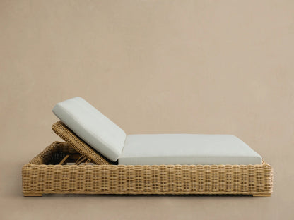 Close-up of the adjustable reclining back of the Montauk Outdoor Double Chaise, showing natural resin wicker and a light blue cushion.