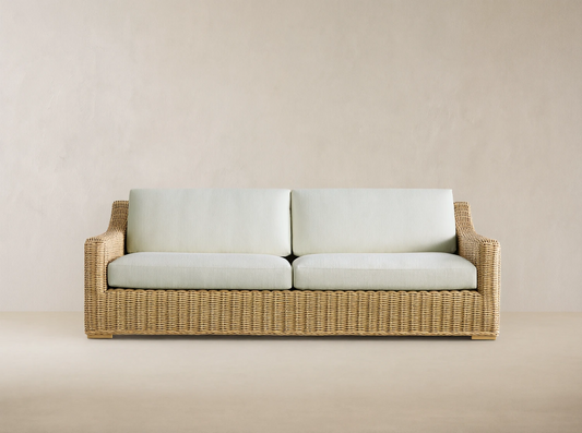 Front view of Montauk Outdoor Sofa, with light natural woven resin wicker and two pale green cushions.