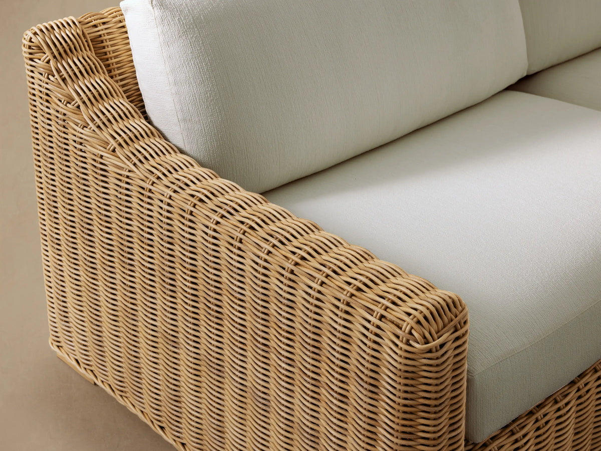 Front view of Montauk Outdoor Sofa, with light natural woven resin wicker and two pale green cushions.