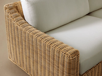 Front view of Montauk Outdoor Sofa, with light natural woven resin wicker and two pale green cushions.
