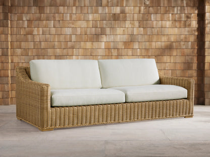 Close-up of the natural woven resin wicker armrest and light cream cushions of the Montauk Outdoor Sofa.