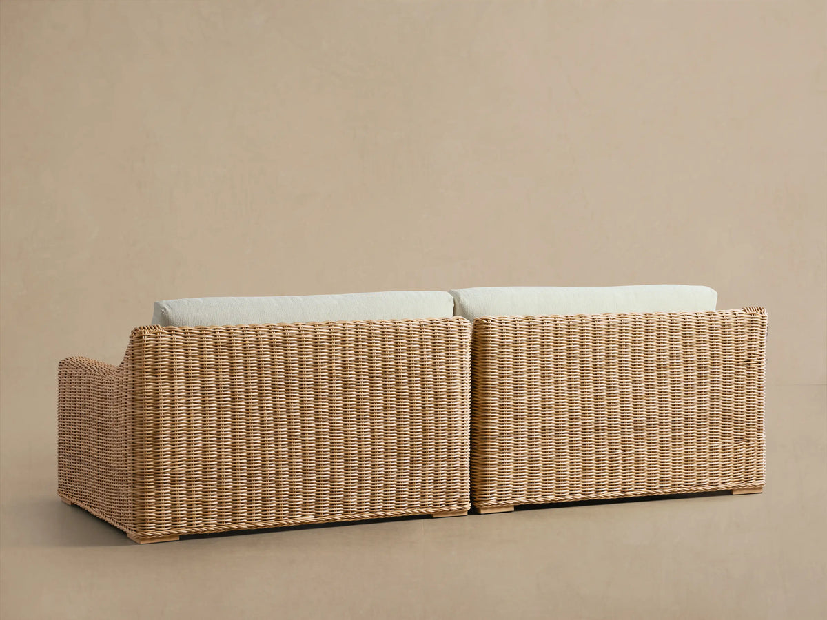 Close-up of Montauk Outdoor Two-Piece Sectional, light brown woven resin wicker arm and back with cream cushions.