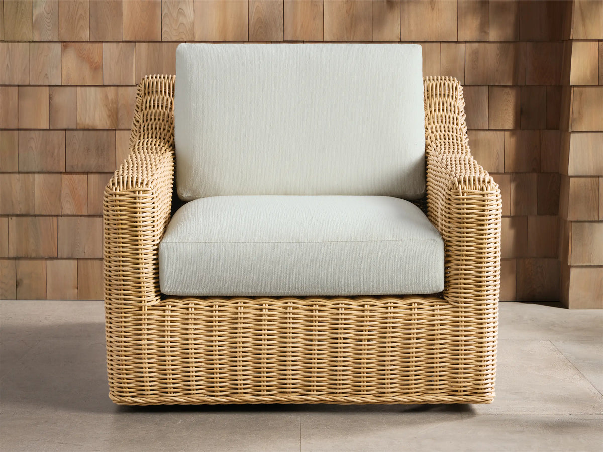 Montauk Outdoor Swivel Chair, light tan woven resin wicker with cream cushions, viewed from front-right on a patio.