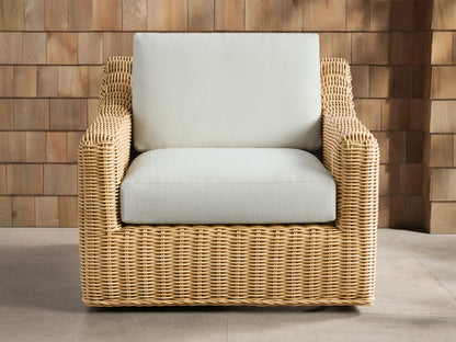 Montauk Outdoor Swivel Chair, light tan woven resin wicker with cream cushions, viewed from front-right on a patio.