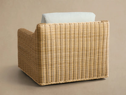 Close-up, angled view of Montauk Outdoor Swivel Chair, showing light brown woven resin wicker frame and light grey cushions.