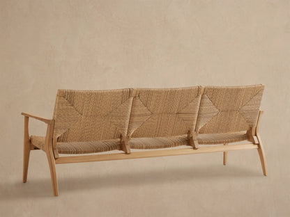 Mustique Outdoor Sofa: close-up, angled view of light teak frame, natural handwoven all-weather wicker with geometric patterns.