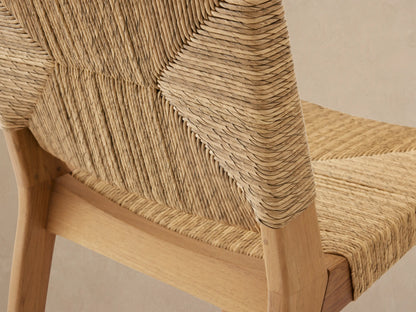 Mustique Outdoor Barstool, light teak wood frame with woven beige wicker seat & back, front view, in sunlit room.