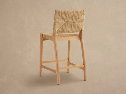 Close-up of Mustique Outdoor Counter Stool, showcasing light natural teak wood frame and intricately woven light brown wicker back and seat.