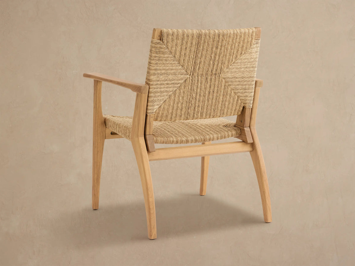 Mustique Outdoor Dining Arm Chair, close-up. Natural teak frame with light brown woven wicker seat and back in varied patterns.