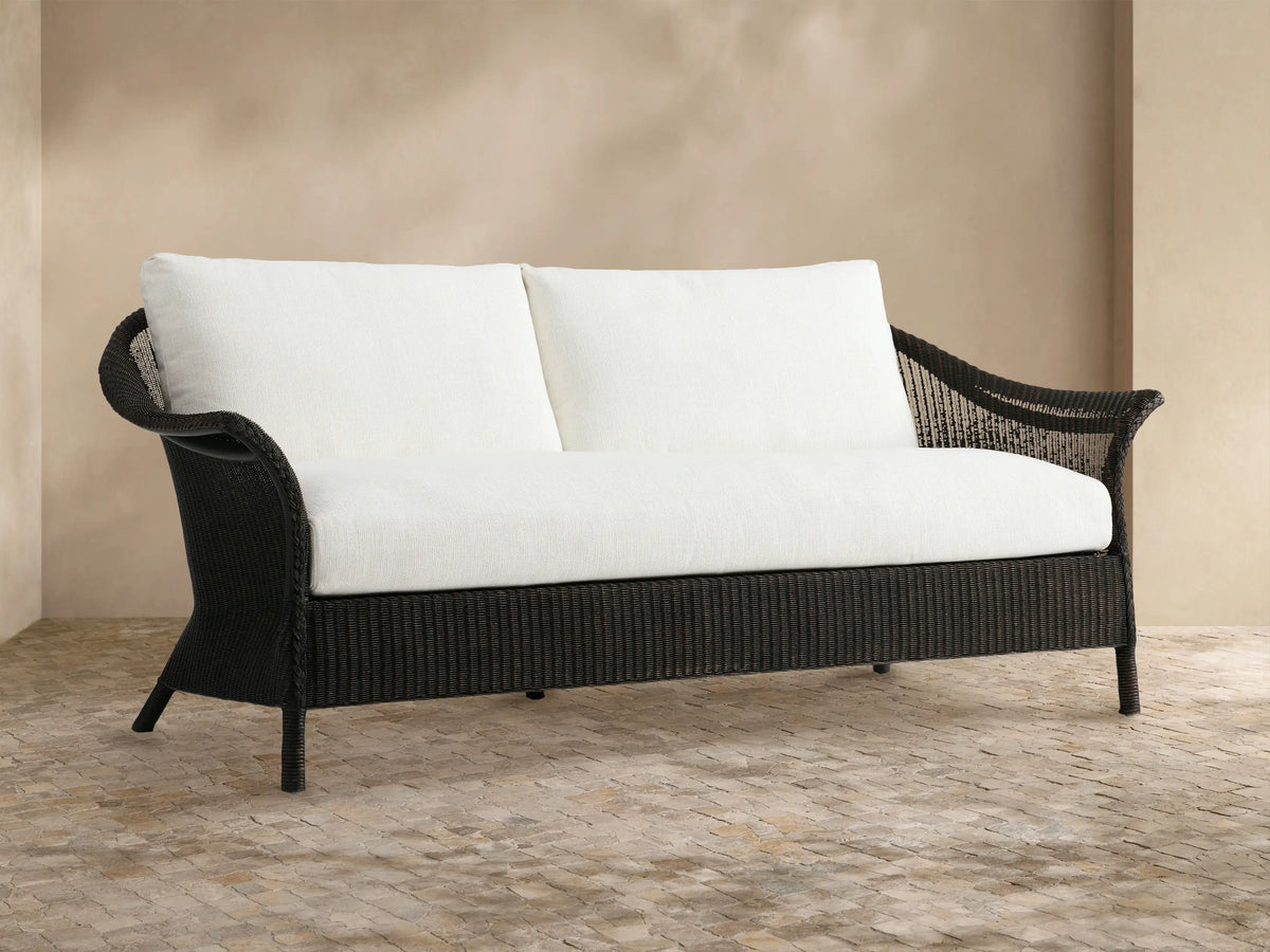 Nantucket Sunroom Sofa with dark brown woven rattan frame and white Eden Snow cushions, in a sunroom against a tan wall.