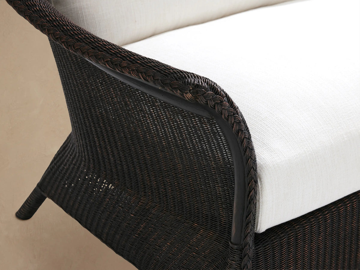 Nantucket Sunroom Sofa with dark woven frame & Eden Snow white cushions, curved arms, on a tiled floor.