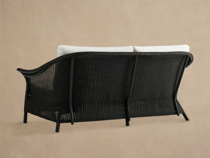 Nantucket Sunroom Sofa close-up: dark brown woven wicker armrest with braided trim and white Eden Snow cushion.