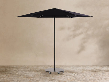 Black Nata Outdoor Round Umbrella, fully open, with a tall pole and dark grey wheeled base, on textured outdoor flooring.
