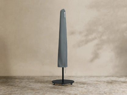 Black Nata Outdoor Round Umbrella, fully open, with a tall pole and dark grey wheeled base, on textured outdoor flooring.