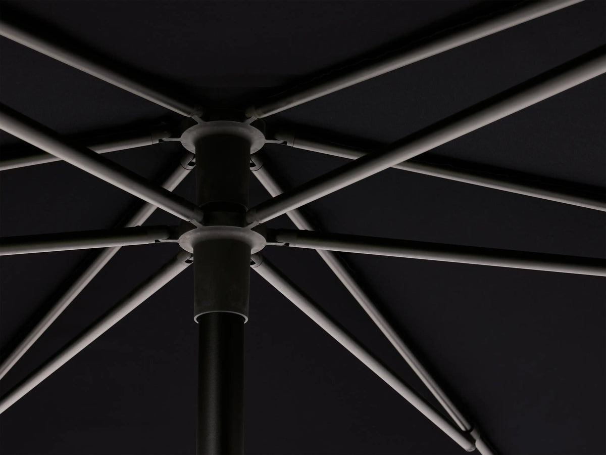 Close-up of Nata Outdoor Round Umbrella, dark blue canopy folded vertically & secured with matching strap with buckle.