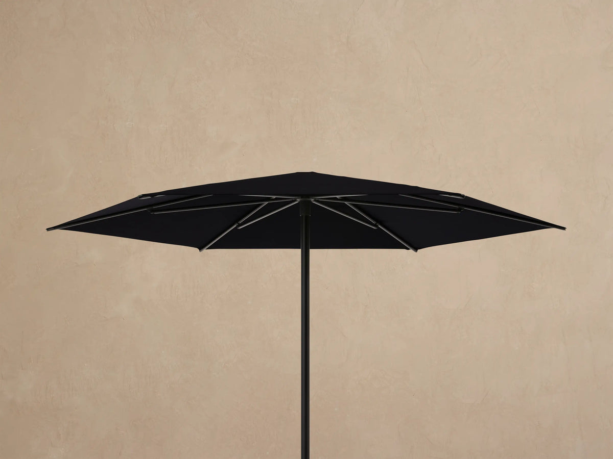 Underside view of a Nata Outdoor Round Umbrella. Black canopy and dark gray aluminum frame ribs converge at the center.