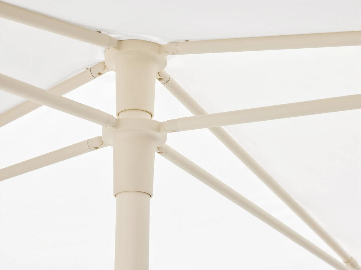 White Nata 79" Outdoor Square Umbrella canopy, viewed from above, showing its square shape and central cap against a beige wall.