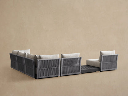 Naxos Outdoor Sectional close-up: light gray fabric cushions, dark gray woven rope armrest, black metal frame.