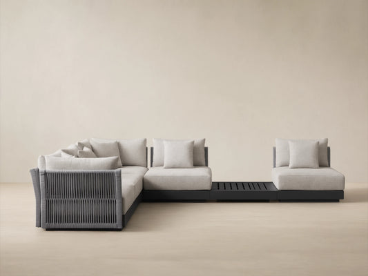 Naxos Outdoor Six-Piece Sectional: L-shaped light grey outdoor sectional with dark grey woven details, single chair, and slatted table.