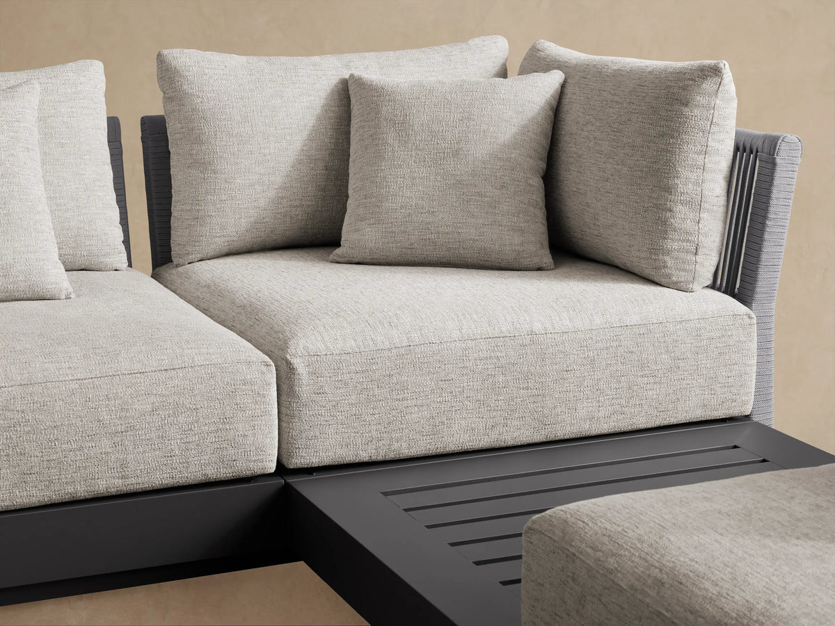 Naxos Outdoor Seven-Piece Sectional, L-shaped, with light grey cushions & dark grey frame, including a slatted chaise on patio.