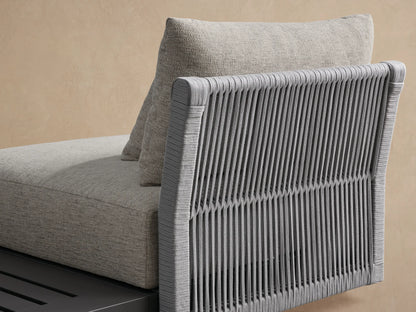 Naxos Outdoor Three-Piece Sectional with dark gray frames, light gray cushions, and slatted end table on a beige patio.