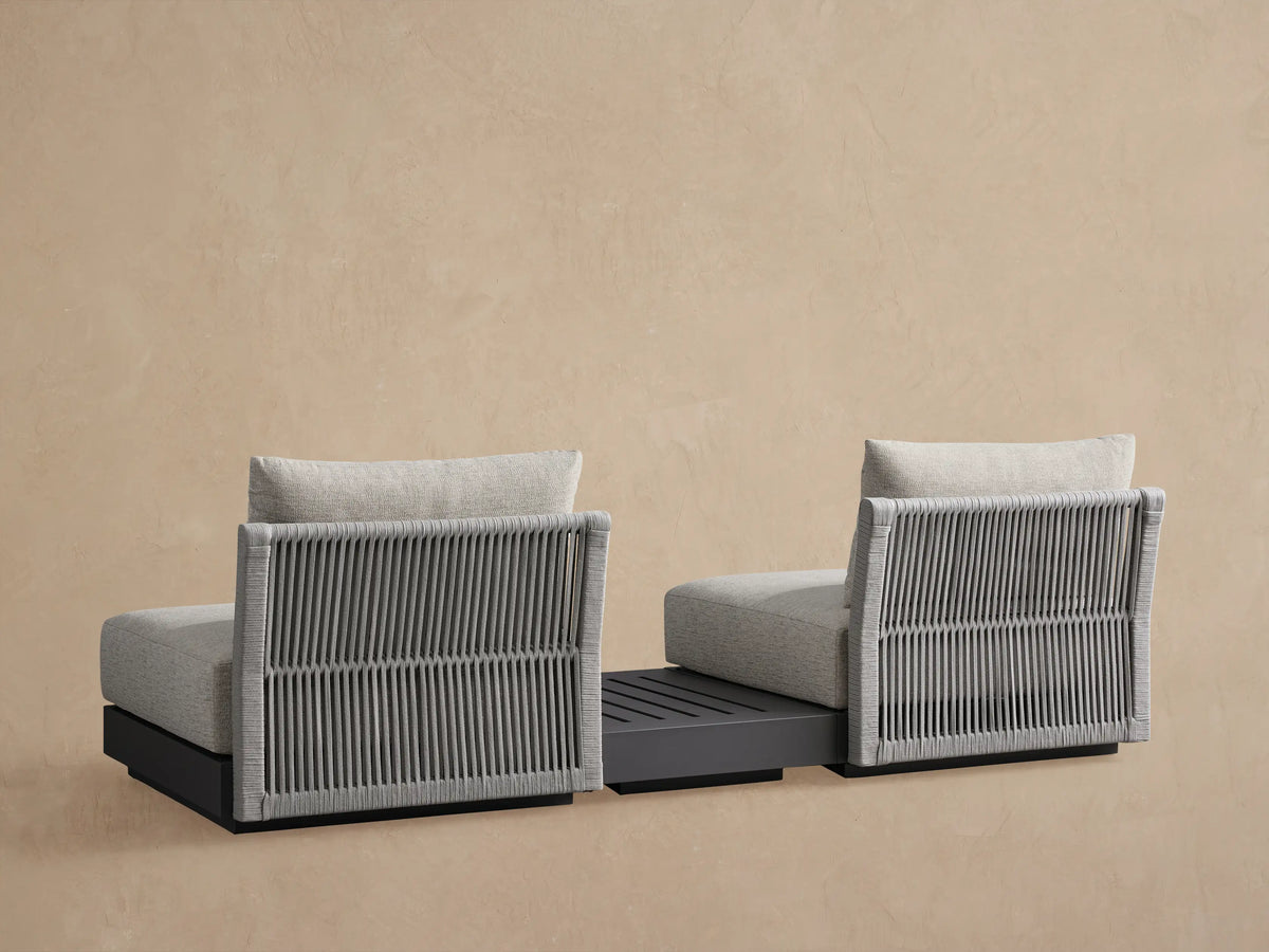 Side view of Naxos Outdoor Sectional with gray woven rope back, light gray cushions, and dark slatted end table.