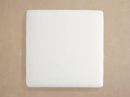Angled close-up of Naxos Outdoor Ottoman. Thick white textured cushion sits on a dark gray rectangular metal frame.