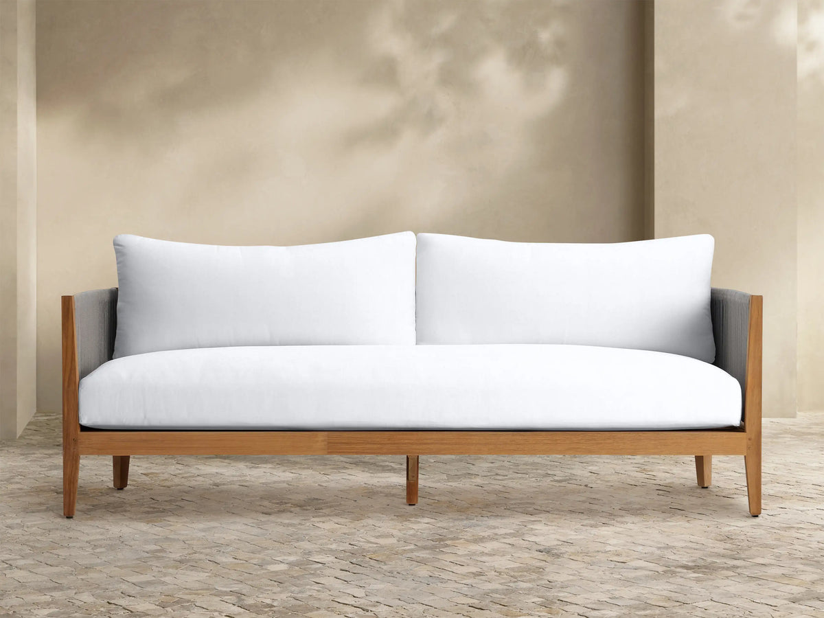 Front view of a two-seater outdoor sofa with plush white Newport Water-Repellent Replacement Cushions on a tiled patio.