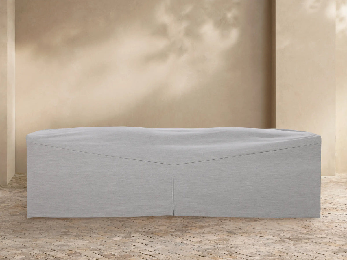 White Newport Outdoor Collection Agora?? covers on a sofa, chaise, and armchair, displayed on a paved patio against a beige wall.