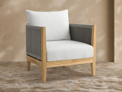 Newport Outdoor Lounge Chair with natural teak frame, dark grey woven rope arms, and light Eden Snow cushions on an outdoor patio.