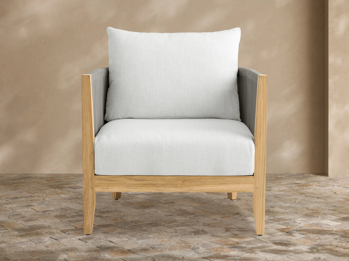 Newport Outdoor Lounge Chair with natural teak frame, dark grey woven rope arms, and light Eden Snow cushions on an outdoor patio.