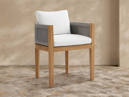 Newport outdoor dining arm chair: natural teak wood frame, gray woven rope arms, white Eden Snow cushions, on stone tile.