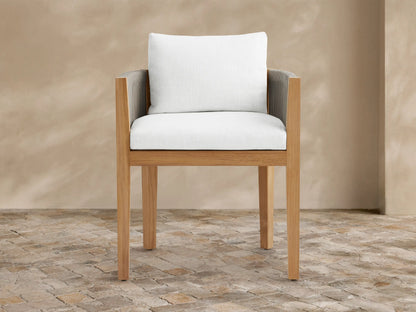 Newport outdoor dining arm chair: natural teak wood frame, gray woven rope arms, white Eden Snow cushions, on stone tile.