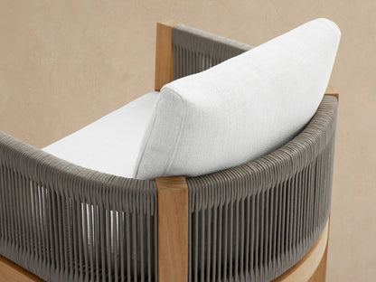 Newport Outdoor Dining Arm Chair with golden teak frame, grey woven arms, and crisp white Eden Snow cushions on a tiled floor.