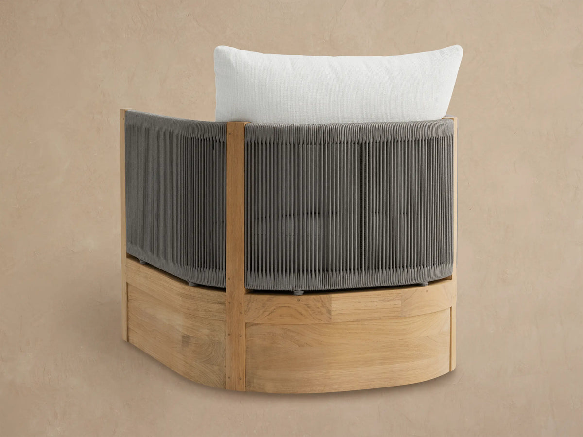 Angled view of a Newport Outdoor Swivel Chair with light teak frame, grey woven rope sides, and white seat and back cushions.