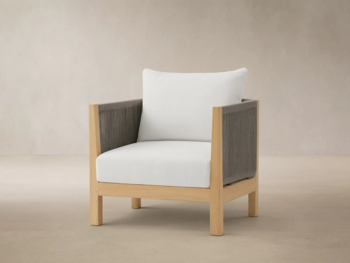 Newport Outdoor Swivel Chair with natural teak frame, dark grey rope arms, and white cushions on a tiled patio.