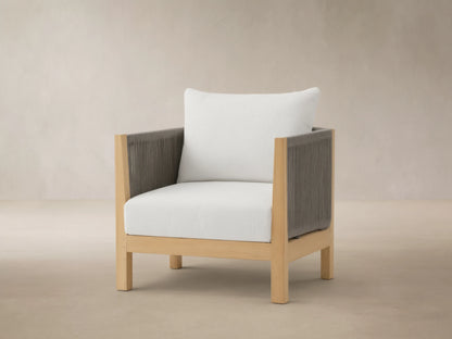Newport Outdoor Swivel Chair with natural teak frame, dark grey rope arms, and white cushions on a tiled patio.