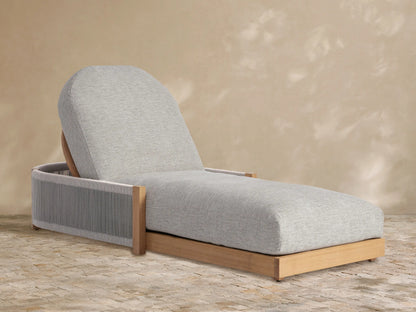Light grey cushioned Newport Outdoor Chaise, teak frame with grey woven sides, angled on a tiled floor against a beige wall.
