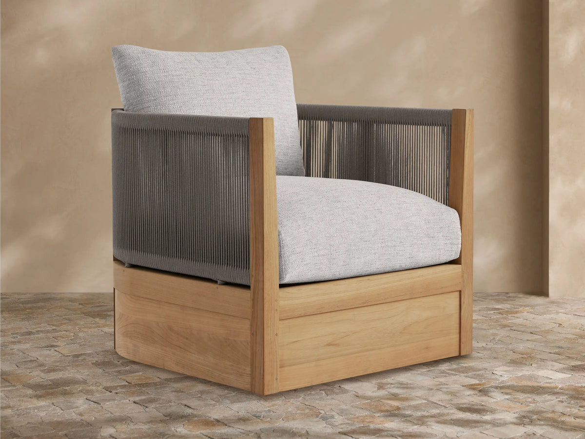 Newport Outdoor Lounge Chair with golden teak wood frame, woven gray rope arms/back, and plush light gray cushions, angled on a patio.