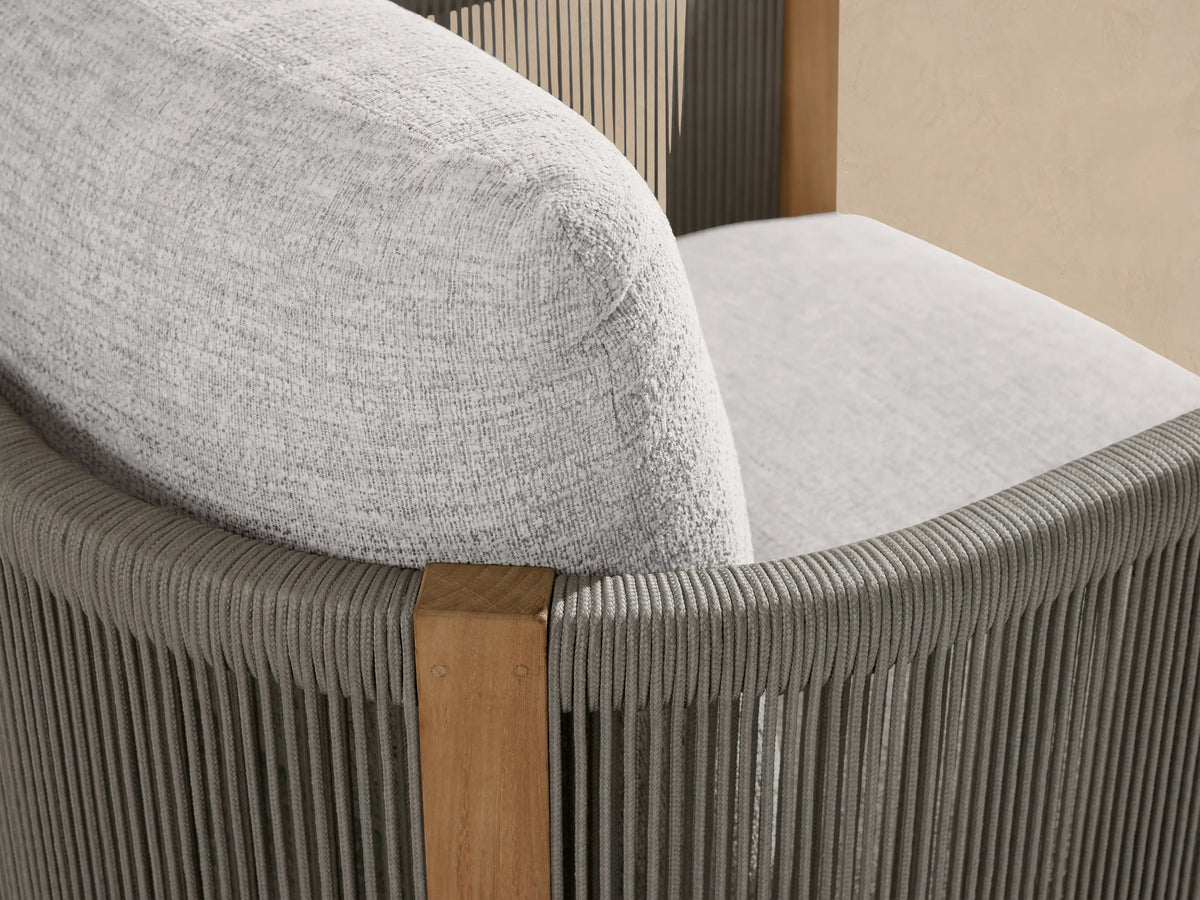 Newport Outdoor Lounge Chair with a natural teak wood frame and light gray textured cushions, front view, on stone pavers.