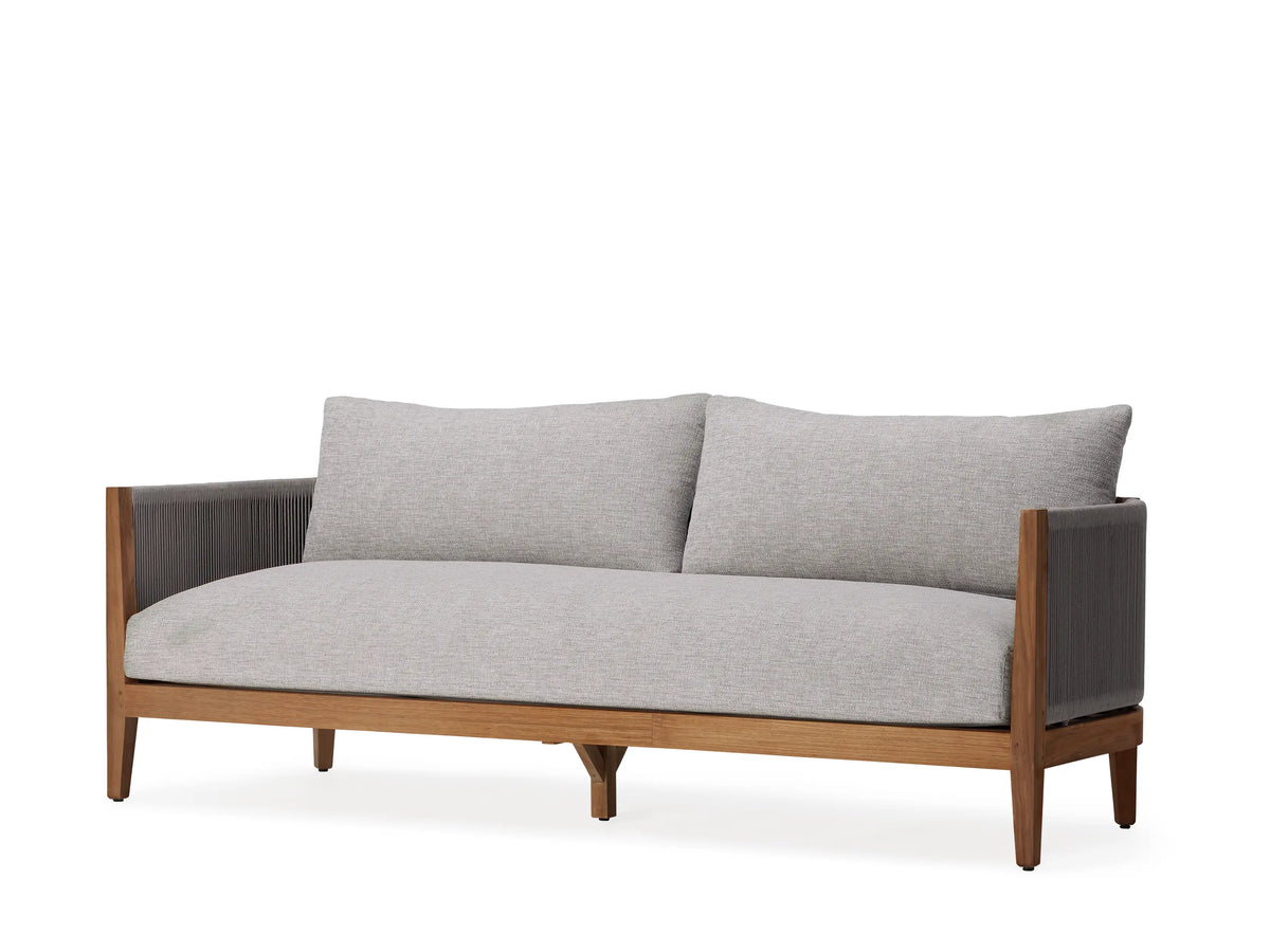 Newport Outdoor Sofa covered with a light gray protective cover, placed on a white terrace with a scenic ocean and mountain view in the background.