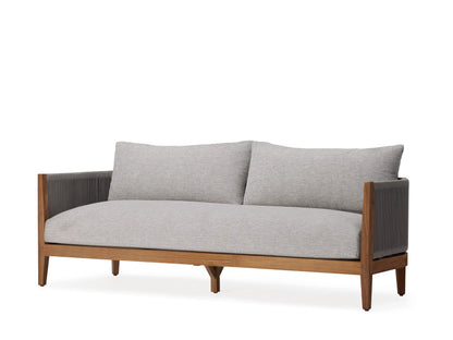 Newport Outdoor Sofa covered with a light gray protective cover, placed on a white terrace with a scenic ocean and mountain view in the background.
