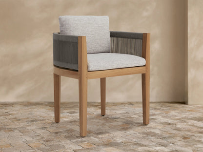Newport Outdoor Dining Arm Chair with natural teak frame, dark grey woven rope arms, and light grey cushions on stone floor.