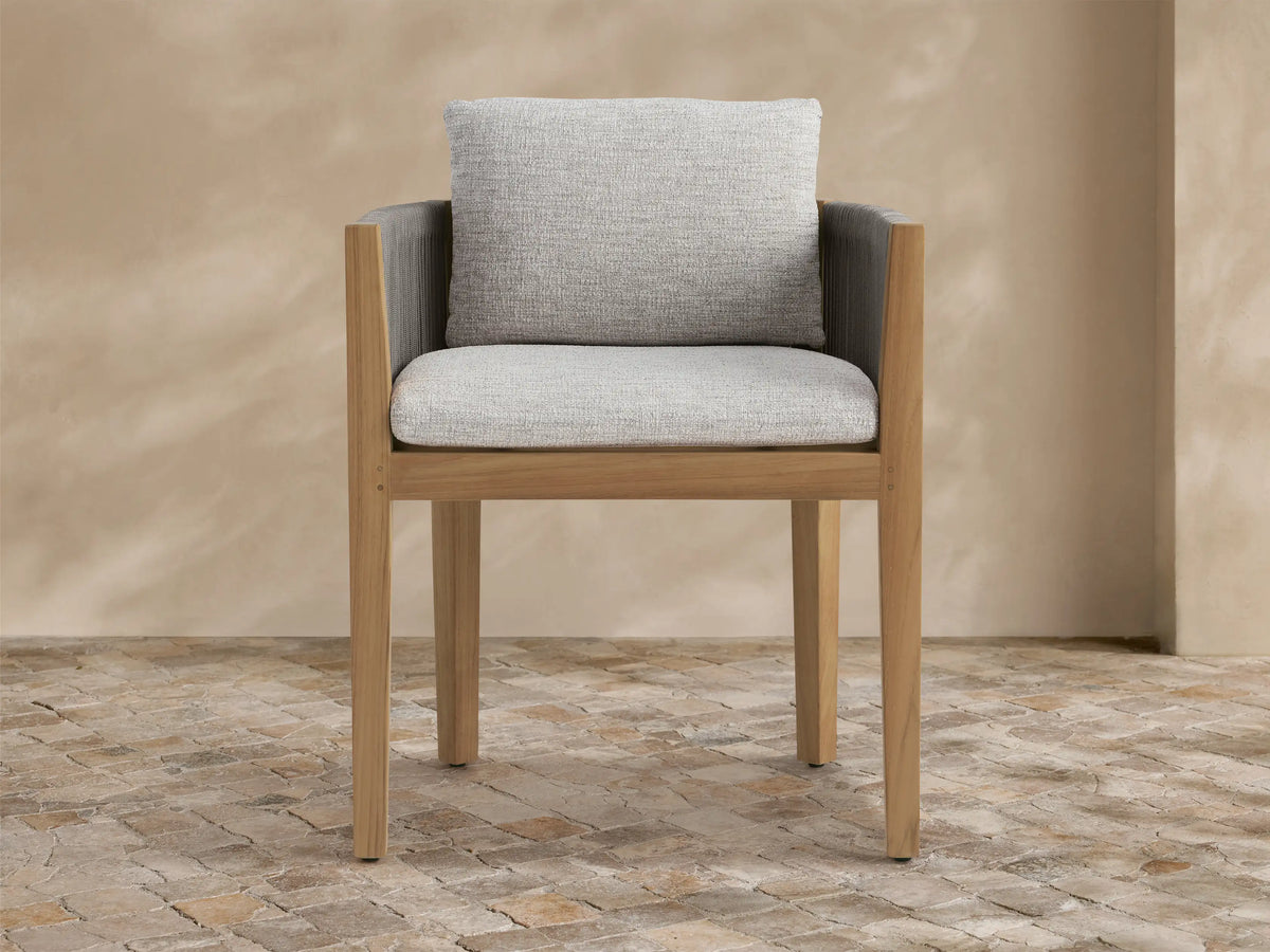 Newport Outdoor Dining Arm Chair with natural teak frame, dark grey woven rope arms, and light grey cushions on stone floor.