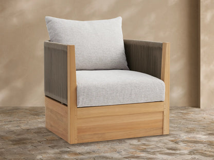 Newport Outdoor Lounge Chair with natural teak frame, dark brown woven sides, and light gray cushions, on a tiled patio.