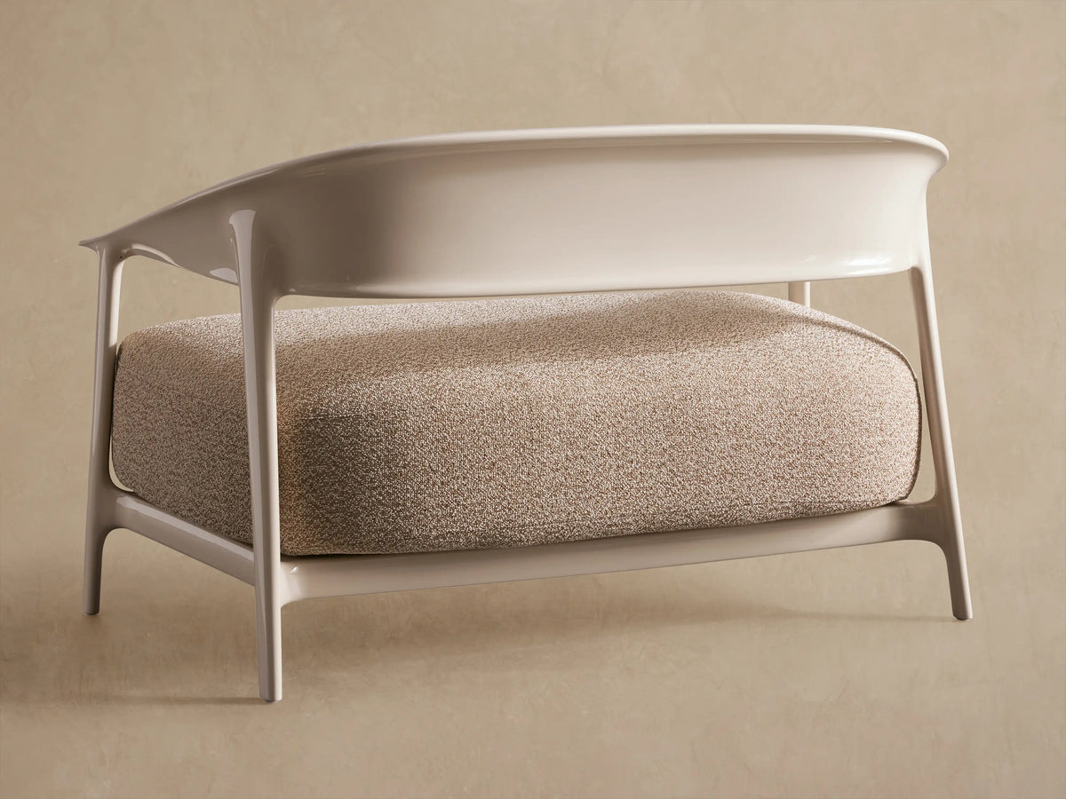 Close-up of Nia Outdoor Sofa: curved light beige armrest over a textured, speckled brown and cream cushion.