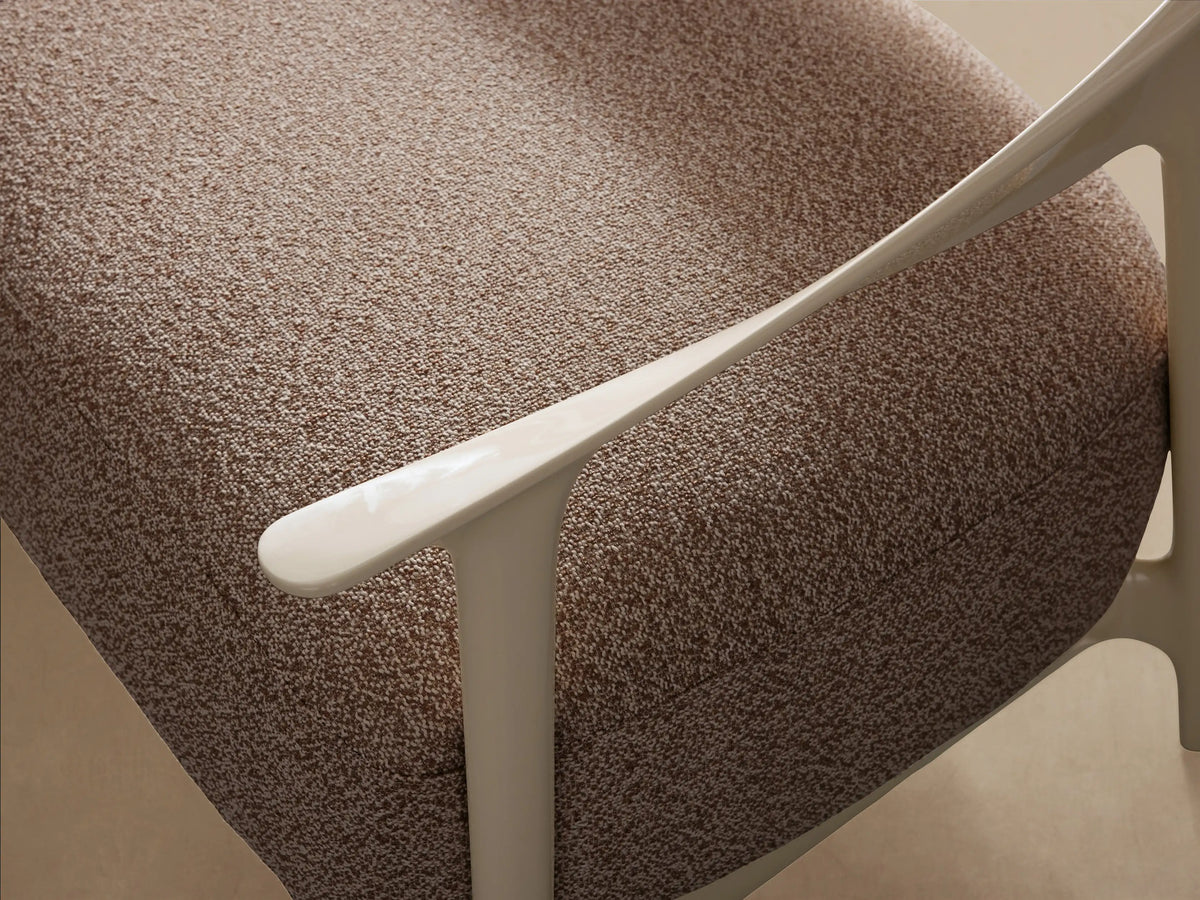 Nia Outdoor Sofa with a sleek, curved light greige frame and a textured, mottled brown cushion on a tiled floor.