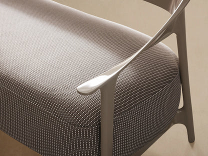 Modern Nia Outdoor Sofa, light taupe curved frame, textured light grey cushions, angled right on a tiled floor.