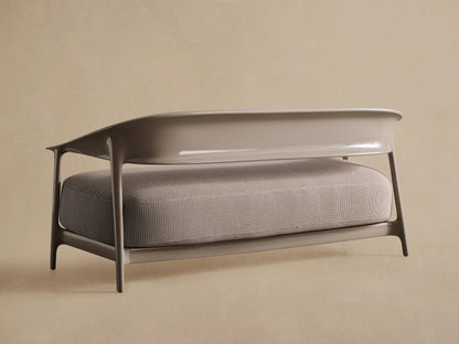 Close-up of Nia Outdoor Sofa. Textured gray fabric with white dotted weave, smooth modern curved light grey armrest.